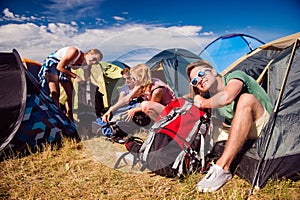 Teenagers sitting on the ground in front of tents