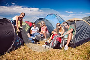 Teenagers sitting on the ground in front of tents