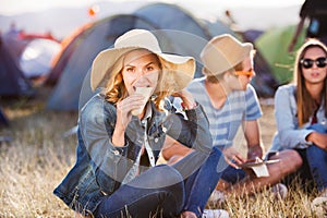Teenagers sitting on the ground in front of tents and eating