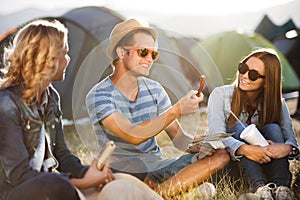 Teenagers sitting on the ground in front of tents and eating