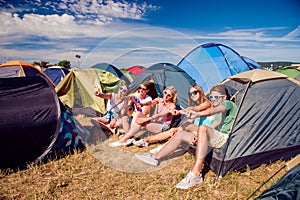 Teenagers sitting on the ground in front of tents