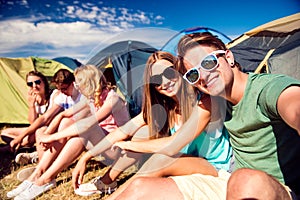 Teenagers sitting on the ground in front of tents