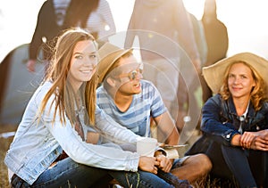 Teenagers sitting on the ground in front of tents, resting