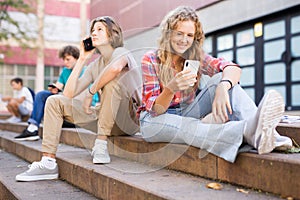 Teenagers with smartphone sitting on stairs outdoors