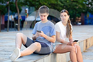 Teenagers with smartphones are siting on the step