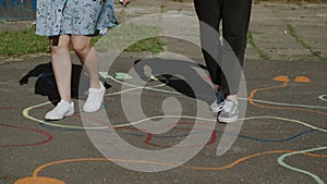 Teenagers in sneakers go through a children maze on street. Close-up of legs.