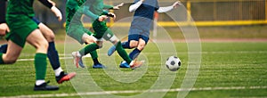 Teenagers in soccer duel. Boys in two football teams running after classic soccer ball