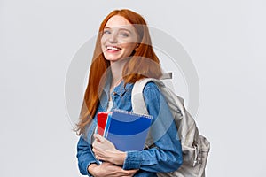 Teenagers, students and education concept. Cheerful lovely redhead female studying, going to univeristy or college photo