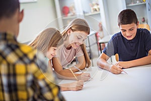 Teenagers students sitting in the classroom and writing.