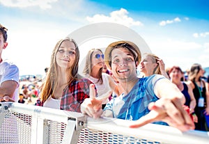 Teenagers at summer music festival, boy showing peace sign