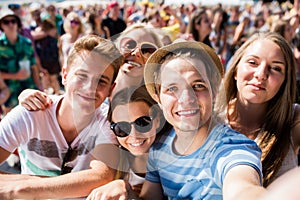 Teenageři na letním hudebním festivalu v davu s selfie