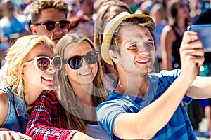 Teenagers at summer music festival in crowd taking selfie