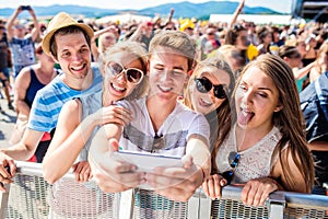 Teenageři na letním hudebním festivalu v davu s selfie