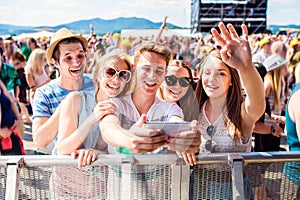 Teenagers at summer music festival in crowd taking selfie photo