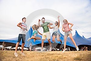 Teenagers at summer music festival dancing and jumping