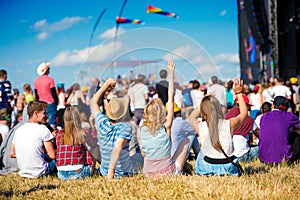 Teenagers, summer music festival, sitting in front of stage photo