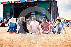 Teenagers, summer music festival, sitting in front of stage