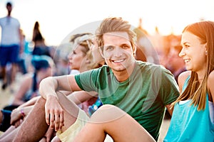 Teenagers at summer music festival, sitting on the ground