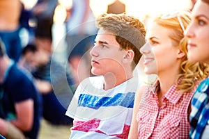 Teenagers at summer music festival, sitting on the ground