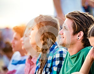 Teenagers at summer music festival, sitting on the ground