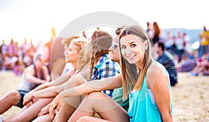 Teenagers at summer music festival, sitting on the ground