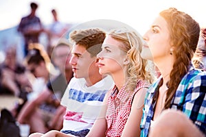 Teenagers at summer music festival, sitting on the ground