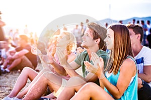 Teenagers at summer music festival, sitting on the ground photo