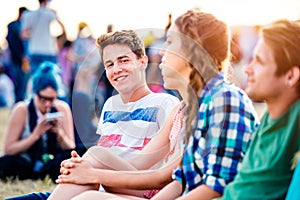 Teenagers at summer music festival, sitting on the ground