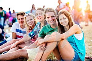 Teenagers at summer music festival, sitting on the ground