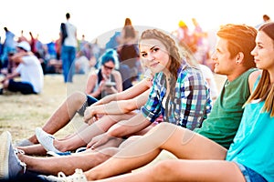 Teenageři na letním hudebním festivalu, sedí na zemi