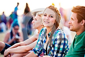 Teenagers at summer music festival, sitting on the ground