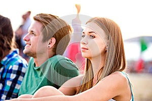 Teenagers at summer music festival, sitting on the ground