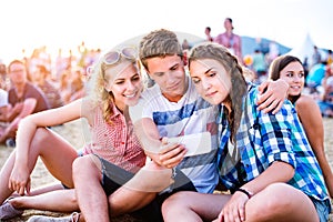 Teenagers at summer music festival, taking selfie with smartphon