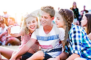 Teenagers at summer music festival, taking selfie with smartphon