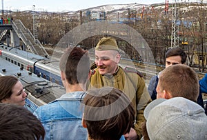 Teenagers talk with a man in the uniform of a soldier of World War II.