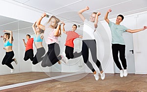 Teenagers with teacher jumping in dance hall