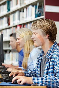 Teenagers working on computers in library