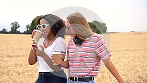 Teenagers young women wearing sunglasses drinking coffee and using their smart phones for social media