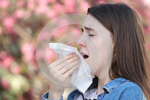 Teeneger girl with polen allergy sneezing in park