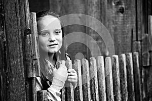 Teengirl standing near rural fence. Black and white photo.