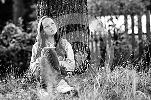 Teengirl writing in a dairy notebook in the park. Black and white photo.