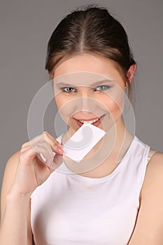 Teenlady in bitting slip of paper. Close up. Gray background