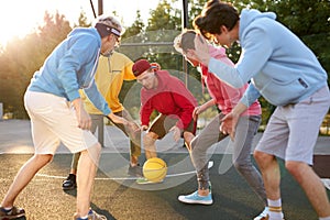 Teens boys playing basketball on outdoor court, playground and having fun