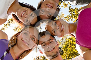 Teens in a circle smiling in park photo