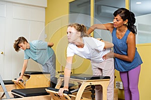 Teens doing pilates exercises with trainer