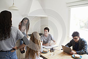 Teens hanging out in kitchen, doing homework and talking