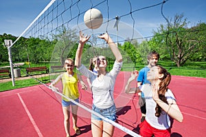 Teens holding arms up and playing volleyball