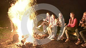 Teens looking at bright campfire.