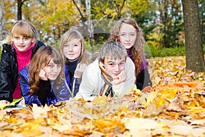 Teens lying on autumnal leaves photo