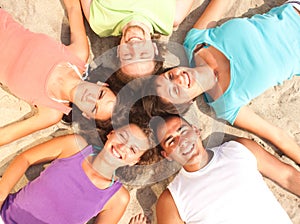 Teens lying on a beach in a circle